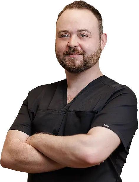 Stefan Brandl, ein Mann mitte dreißig mit kurzen Haaren, hoher Stirn und Vollbart. Er lächelt mit verschränkten Armen freundlich in die Kamera und trägt ein schwarzes T-Shirt